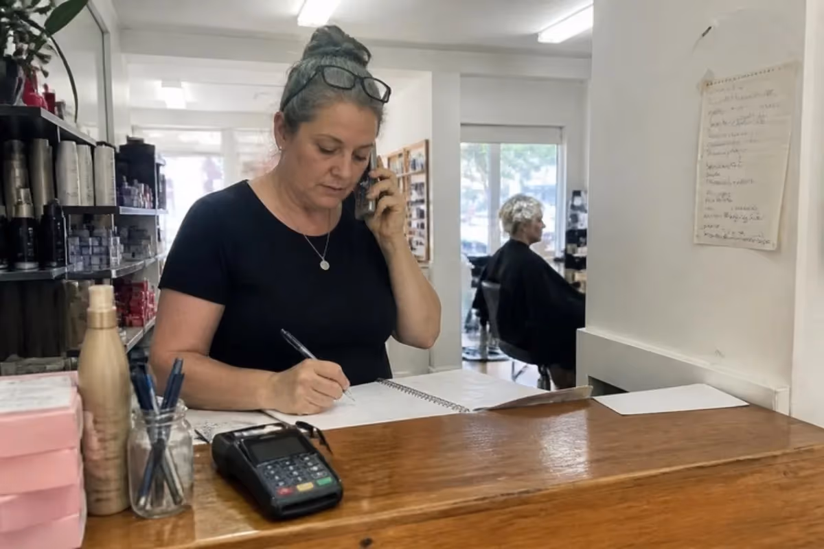 Hair salon owner taking a booking call at the front counter